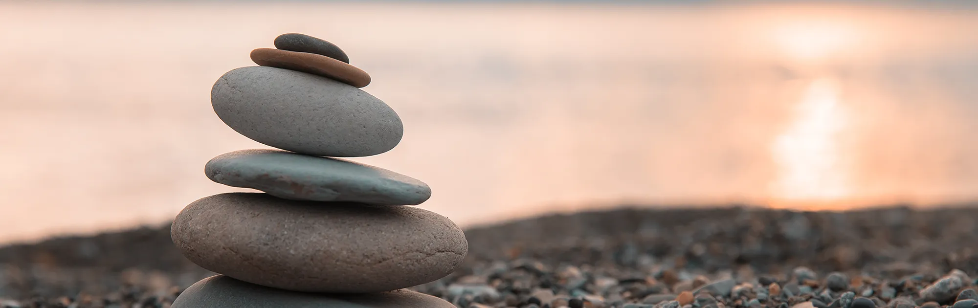 Steinstapel mit Lichtreflexion: Symbol für Balance und innere Stärke durch energetisches Coaching.